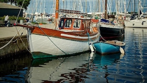 A marina with several boats docked, including a prominent red and white boat in the foreground. - Roskilde Danhostel (Roskilde)