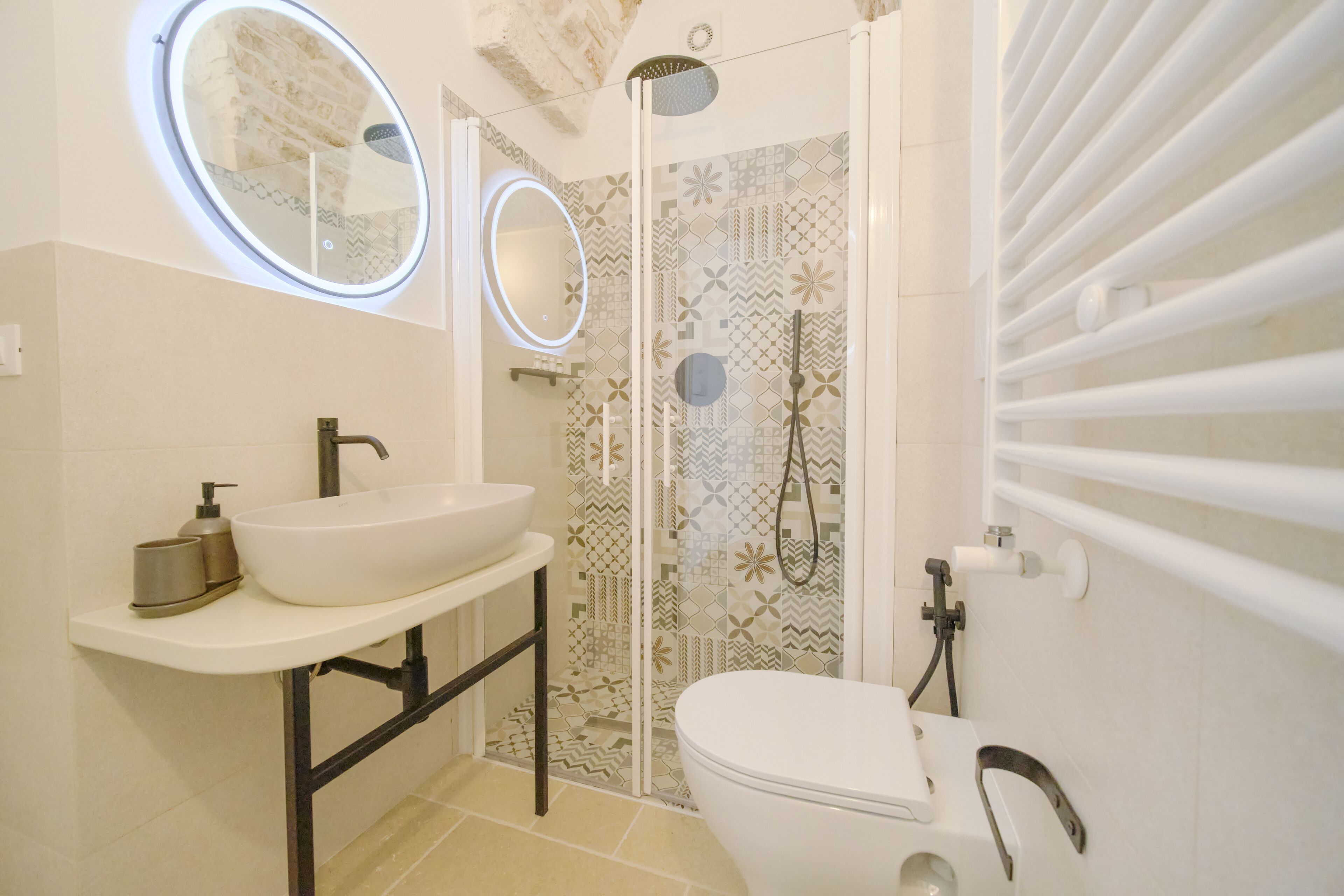 A bathroom with a white sink, a toilet, and a shower area with patterned tiles.
