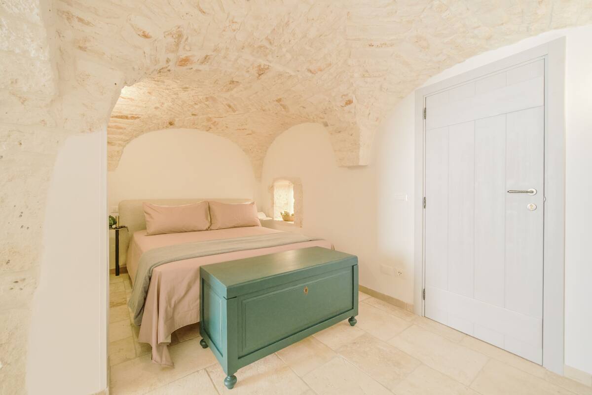 A bedroom with a bed, a dresser, and a white door.