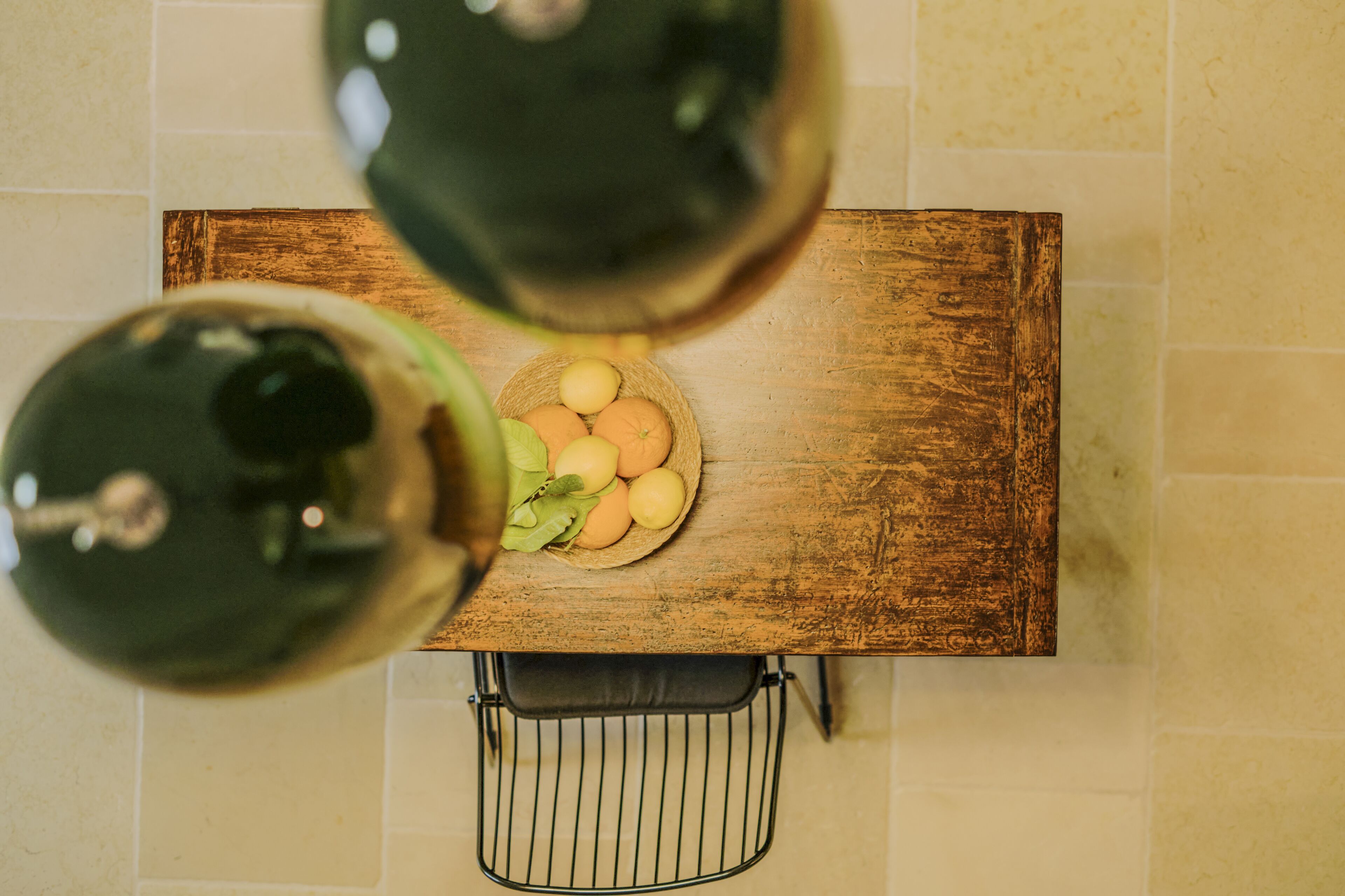 Una mesa de madera con un bol de fruta y una cesta de alambre debajo.