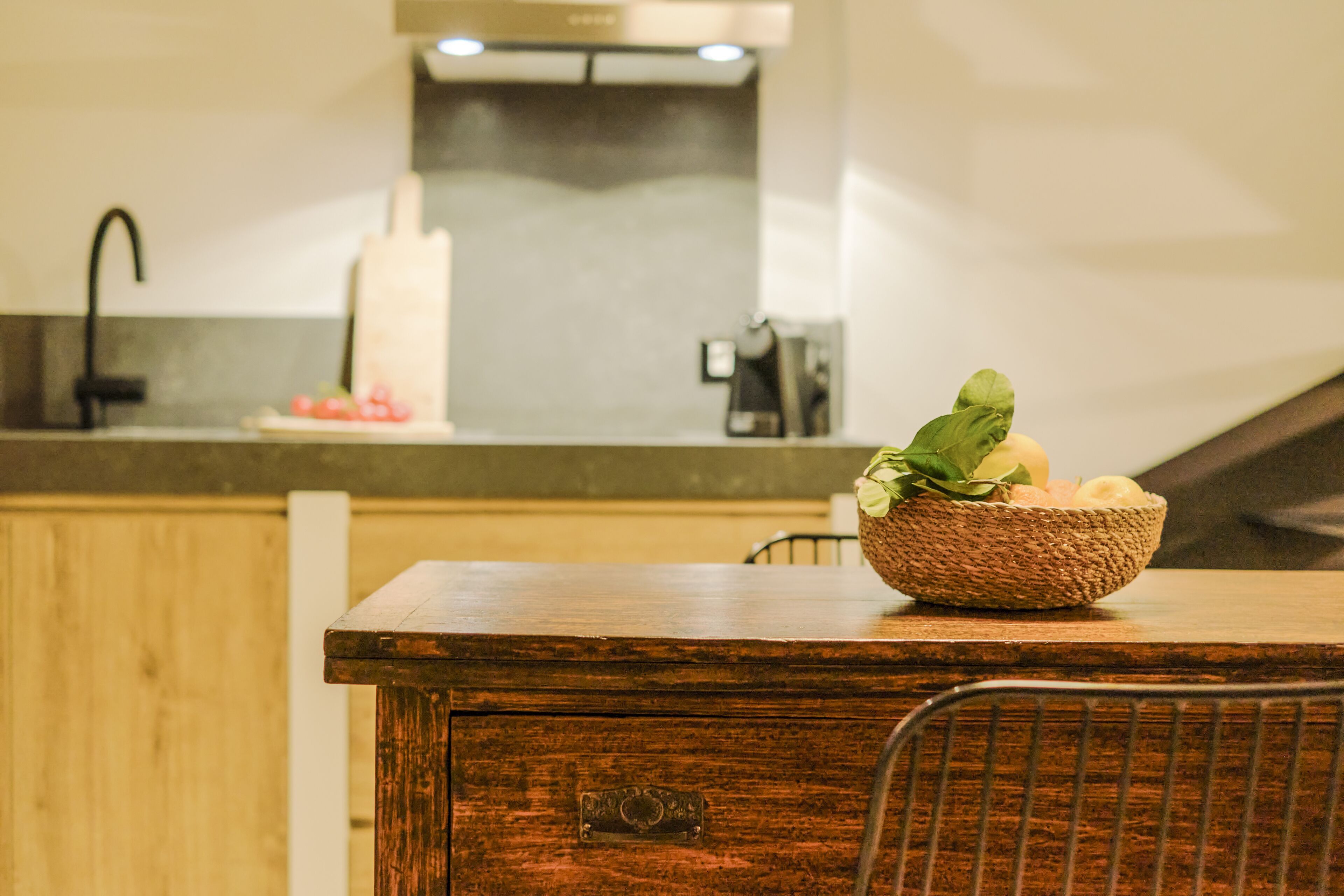 Una mesa de madera para comer con una cesta tejida que contiene verduras.