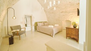 Une chambre à coucher avec un lit, une chaise, une table de chevet et une lampe.
