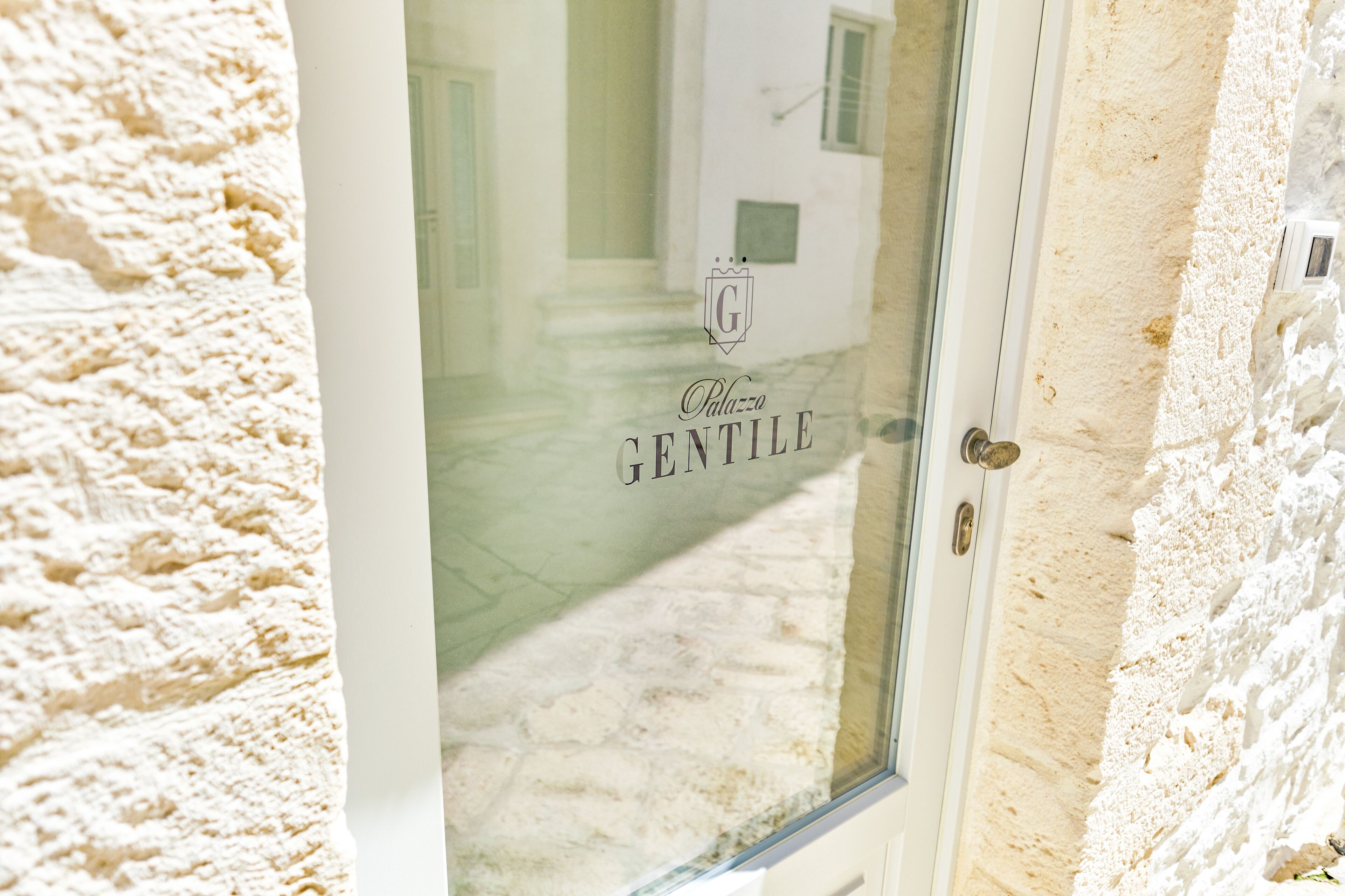 Una puerta con un panel de vidrio que muestra el texto 'Palazzo Gentile'.