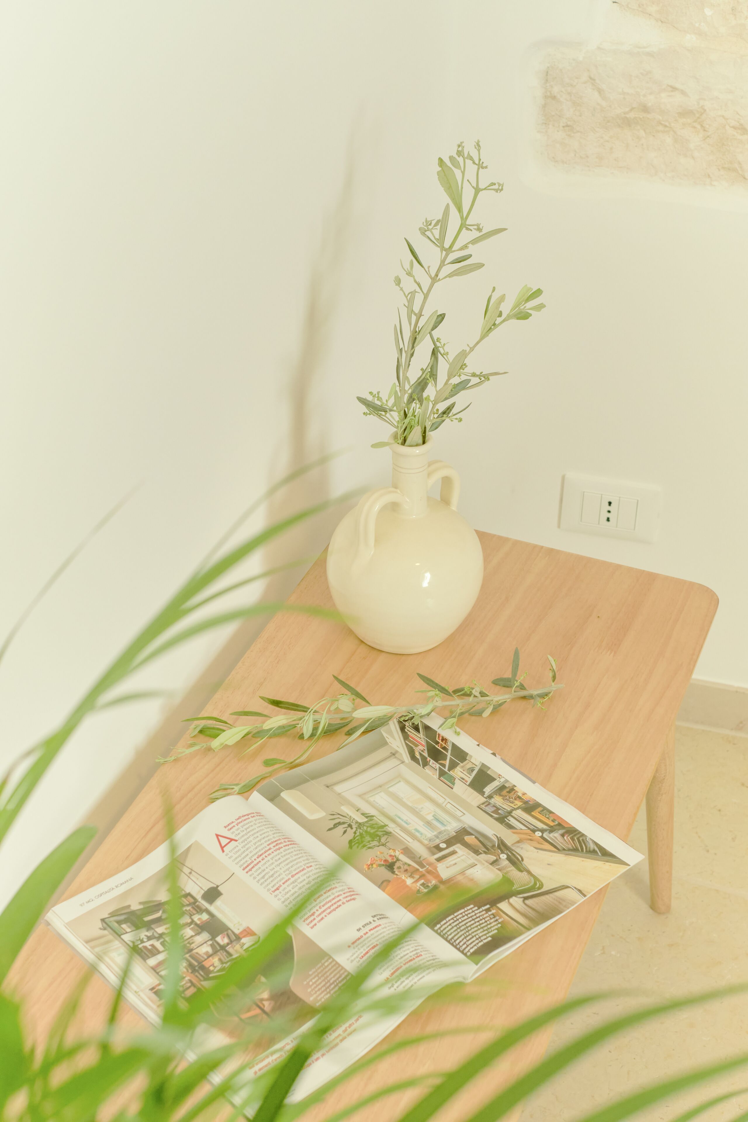 A wooden table with a white vase and a magazine.