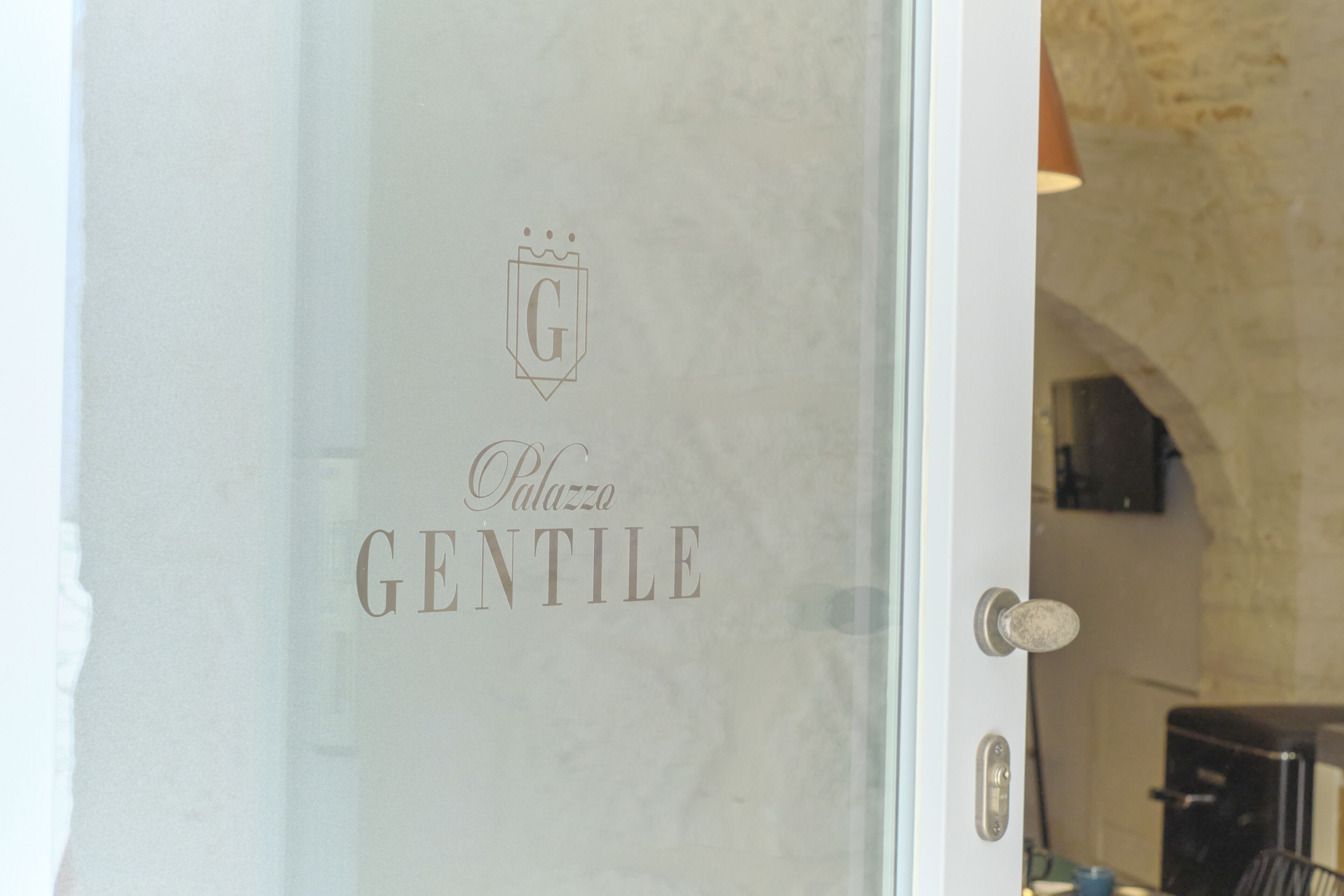 A glass door with the inscription "Palazzo Gentile" and a logo above it.