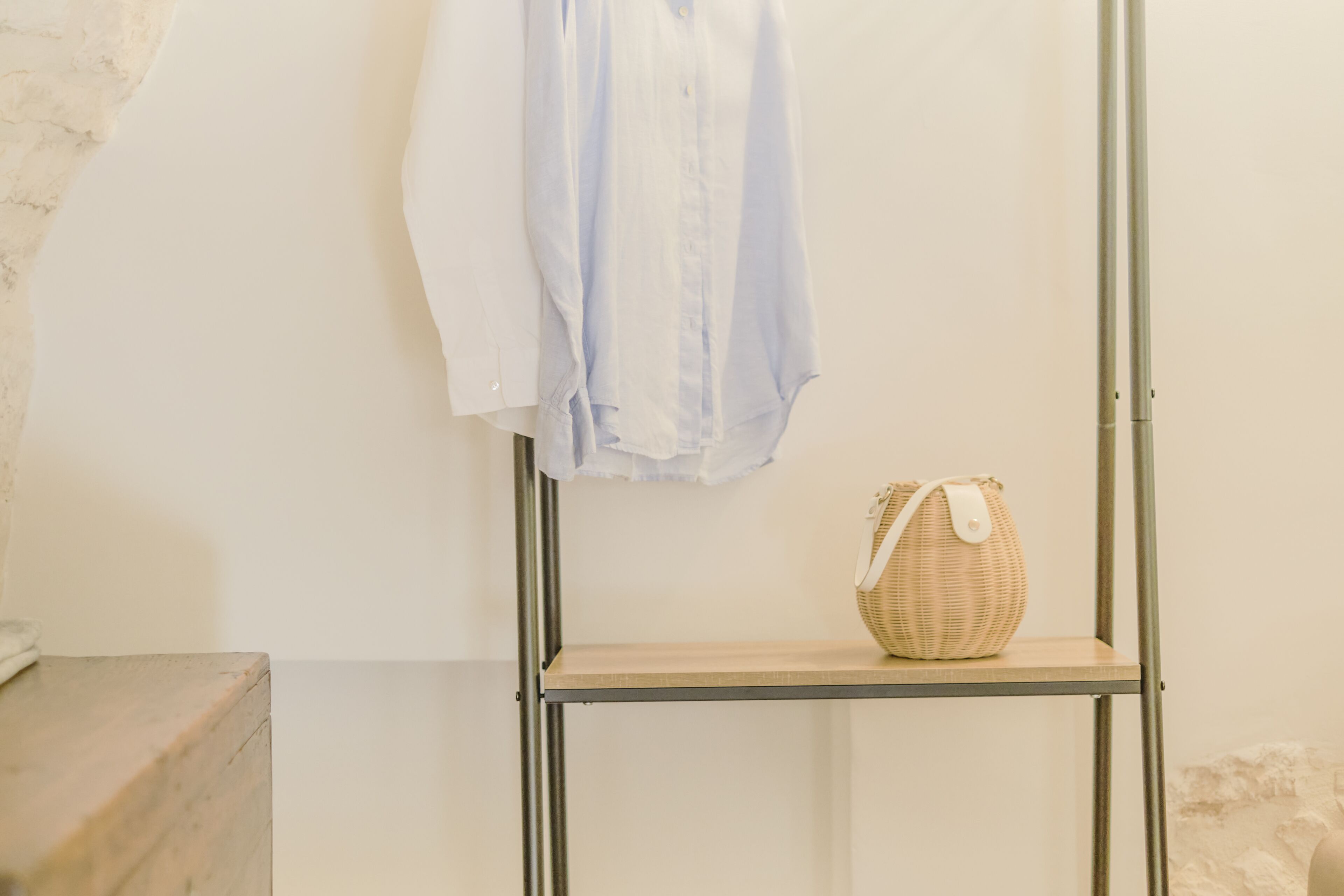 A metal shelf with a wicker basket and a folded shirt.