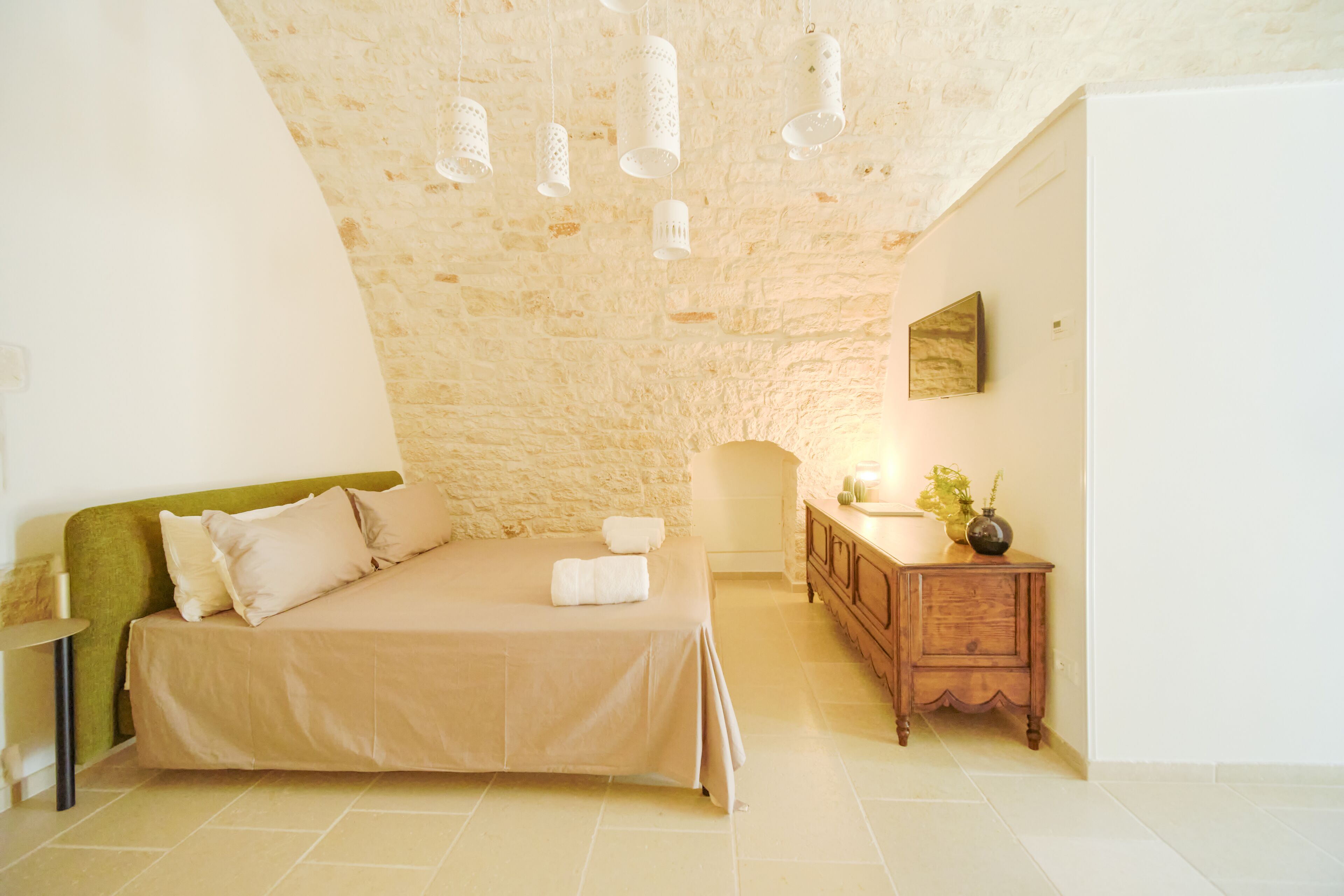 Een slaapkamer met een bed, nachtkastje, lamp en een aan de muur hangend schilderij.