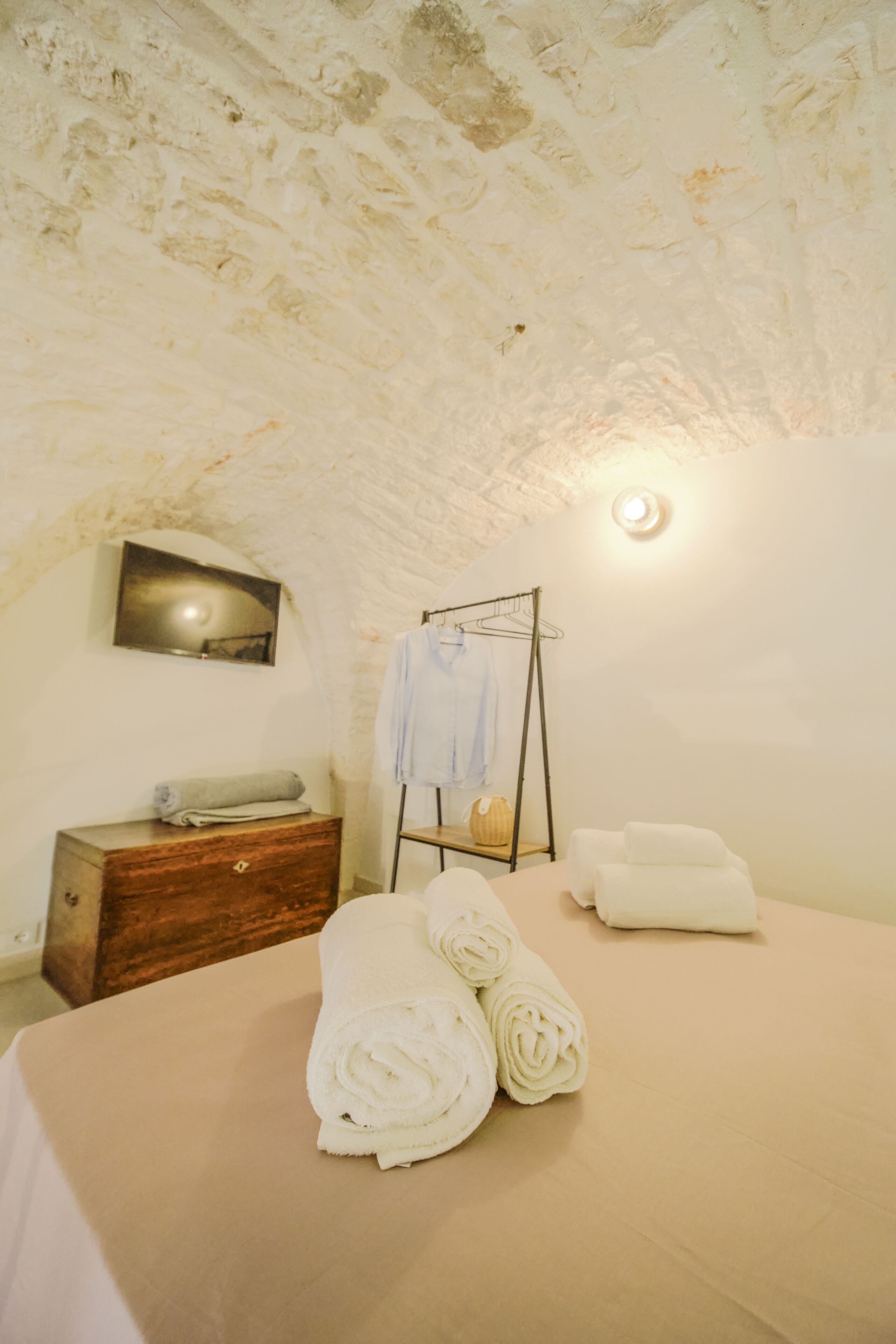 A cozy room with a bed, a wooden dresser, a wall-mounted towel rack, and a painting.