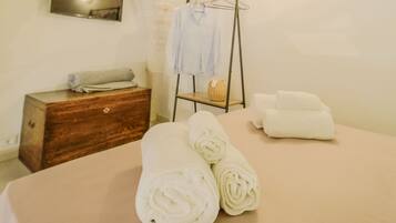A cozy room with a bed, a wooden dresser, a wall-mounted towel rack, and a painting.