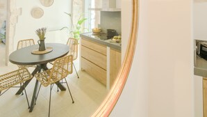 Un coin repas avec une table ronde, des chaises en osier et un luminaire suspendu.