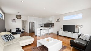 A modern apartment with a living room, dining area, kitchen, and a TV.