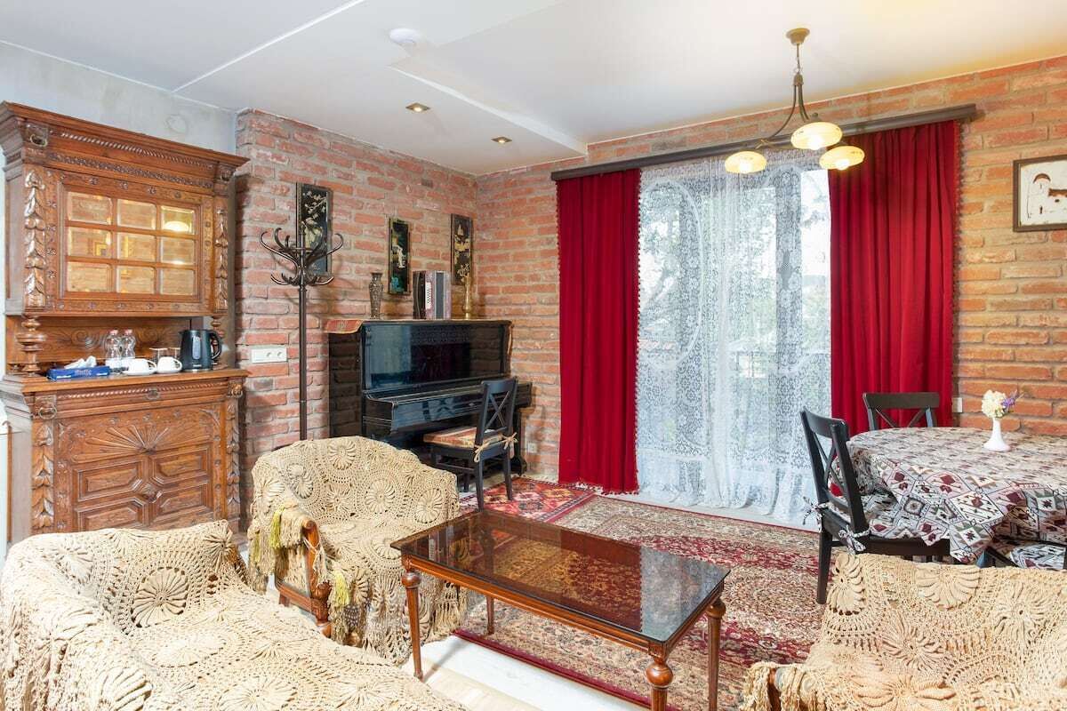 A cozy living room with a brick fireplace, a television, and a dining area with a table and chairs.