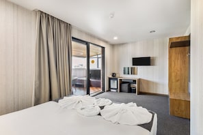 A hotel room with a bed, a TV, a desk, and a sliding door to a balcony. - Brooch Boutique Hotel (Tbilisi)