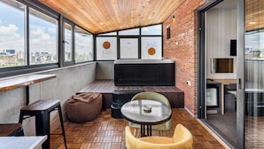 Een modern interieur met houten plafond, grote ramen, zithoek en uitzicht op de stad.
