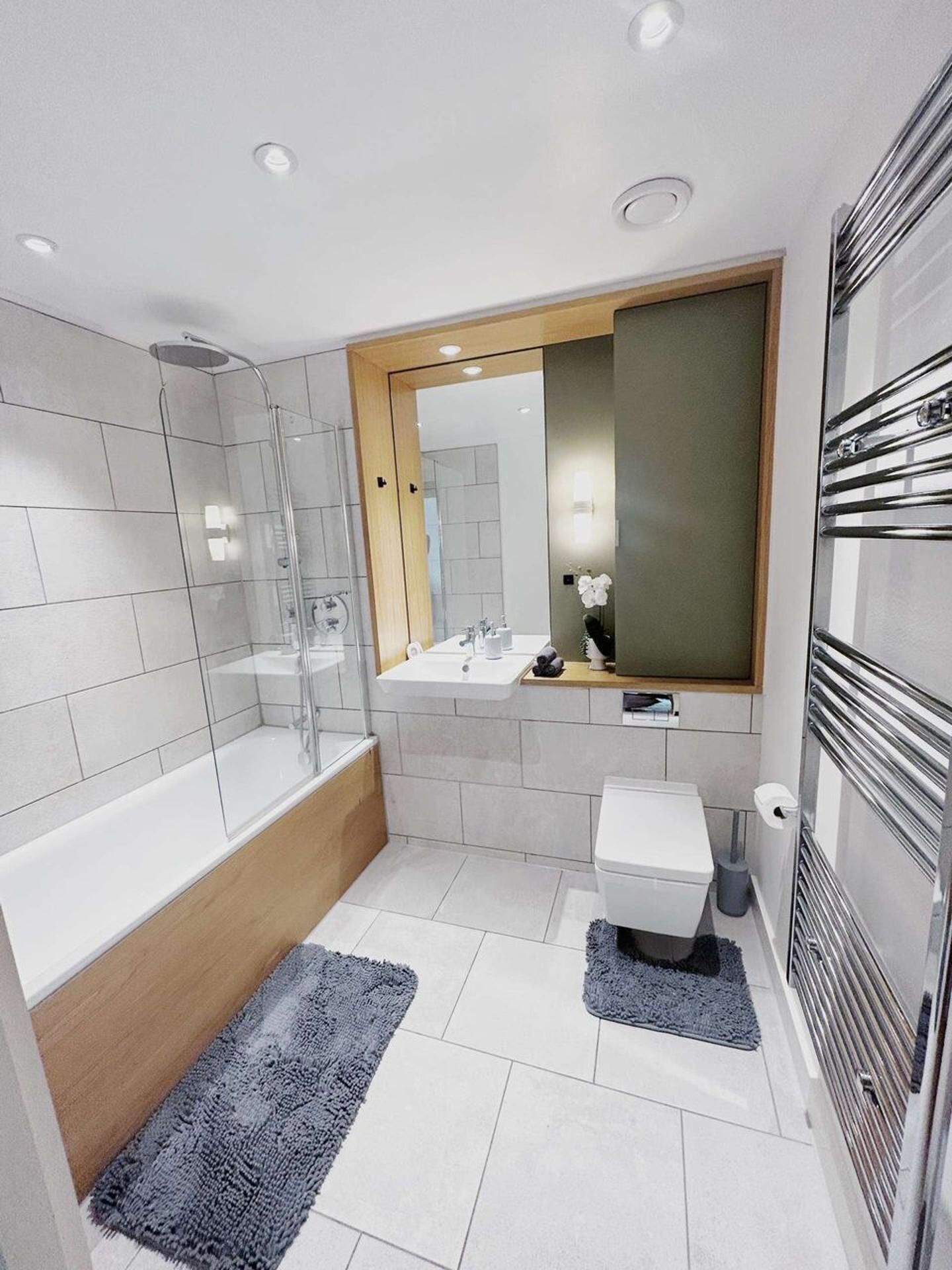 A modern bathroom with a glass-enclosed shower, a freestanding bathtub, a vanity with a mirror, and a toilet.