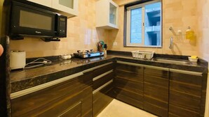 Una cocina moderna con armarios de madera oscura, un microondas negro y un ventanal que proporciona luz natural.