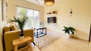 Una sala de estar moderna con un sofá, una mesa de centro, un televisor y una lámpara colgante.