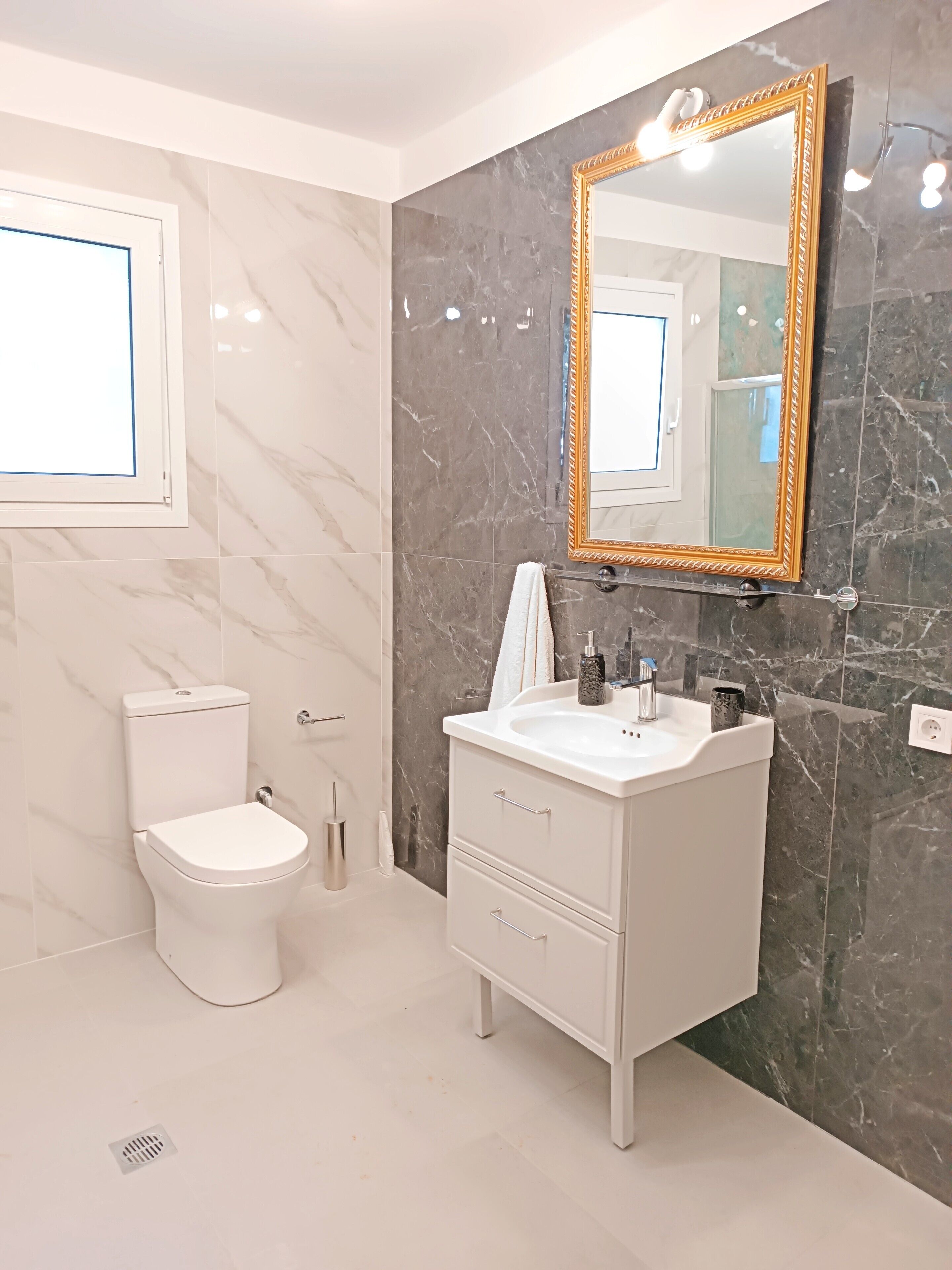 A modern bathroom with a toilet, sink, and mirror.