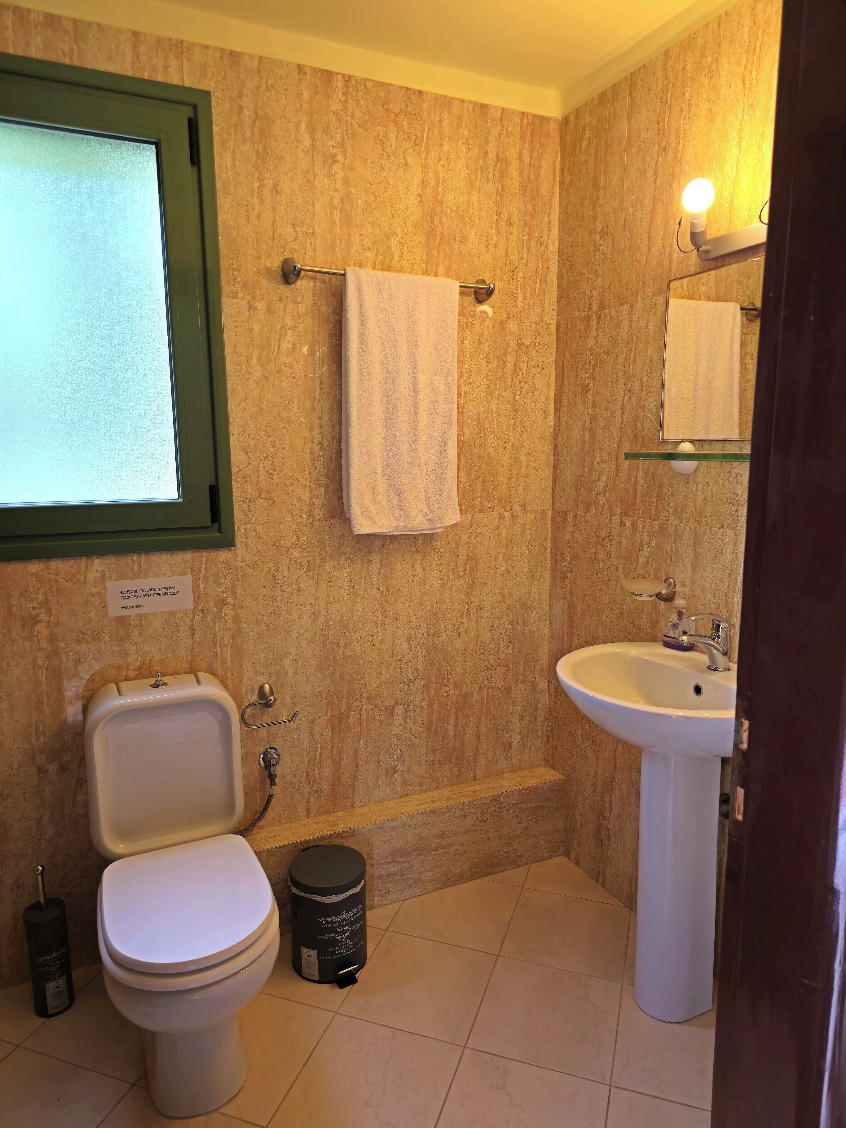 Ein Badezimmer mit Toilette, Waschbecken und einem Handtuch an einem Haken.