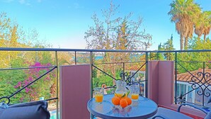 A balcony with a table set for two, featuring a pitcher of orange juice and fresh oranges. - Okeanis Apartments & Suites Adults Only (Kefalonia)