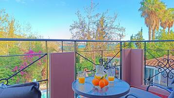 Un balcon avec une table dressée pour deux personnes, agrémenté d’une carafe de jus d’orange et d’oranges fraîches.