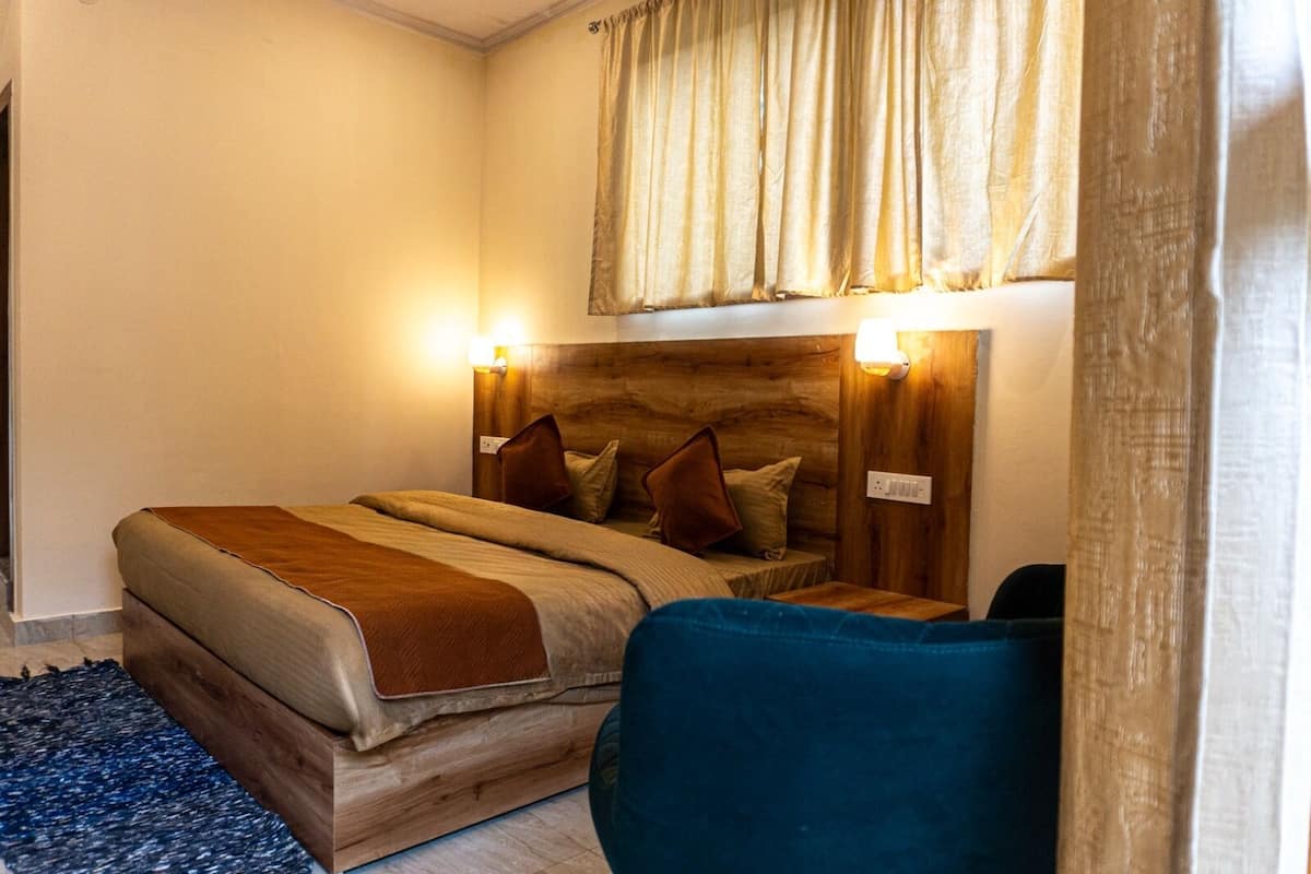 A bedroom with a wooden headboard, a bed with a brown blanket, two bedside lamps, and a blue chair.