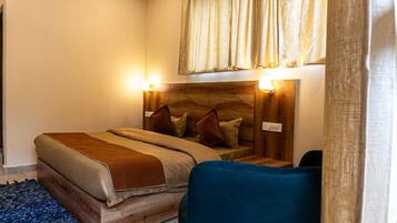 A bedroom with a wooden headboard, a bed with a brown blanket, two bedside lamps, and a blue chair.