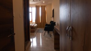 A hallway leading to a living area with a sofa, a dining table, and chairs. - Winter Stone (Dharamshala)