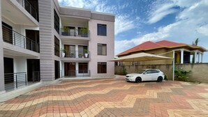 A multi-story building with a car parked in the driveway. - Charming 2-bed Apartment in Kigali (Kigali)