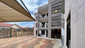 A modern multi-story building with a spacious courtyard featuring a patterned tile floor. - Charming 2-bed Apartment in Kigali (Kigali)