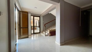 A spacious hallway with a staircase leading to an upper floor, a sliding glass door, and a clean, tiled floor. - Charming 2-bed Apartment in Kigali (Kigali)