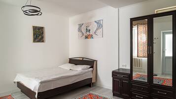 A bedroom with a bed, a wardrobe, a painting, and a rug.
