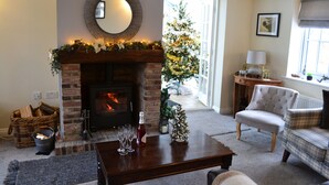 Un salon chaleureux avec une cheminée, un sapin de Noël et un coin salon confortable.