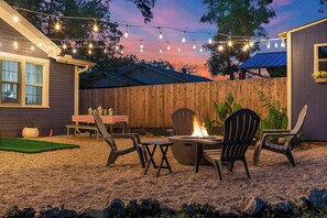 Ein Garten mit Feuerstelle, Gartenmöbeln und Lichterketten.