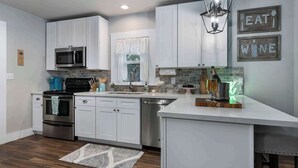 A modern kitchen with white cabinets, a built-in microwave, a stainless steel oven, and a dishwasher. - Blue Bungalow - Fire Pit, Yard Games & more! (Fredericksburg)