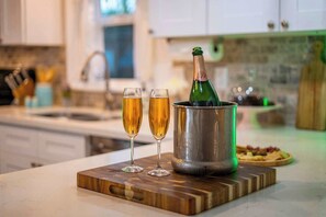 Un comptoir de cuisine avec une bouteille de champagne dans un seau en métal, deux verres à champagne et une planche à découper en bois.