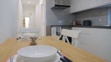 Una mesa de comedor dispuesta con platos blancos, una copa de vino y cubiertos.