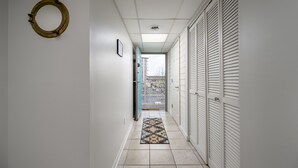 Een hal met een kamerbreed tapijt, een rond object aan de muur en een uitzicht door een open deur op een balkon.