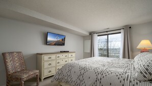 Een slaapkamer met een bed, een stoel, een kast en een televisie aan de muur.