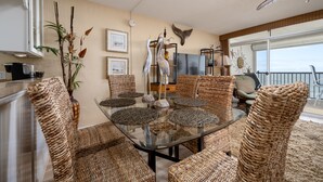A dining area with wicker furniture, a glass table, and a ceiling fan.