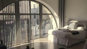 A bedroom with a bed, a large window, and a view of the outside. - Captivating 1-bed Apartment in Swansea (Swansea)