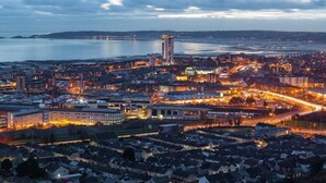 A coastal cityscape at dusk with a prominent high-rise hotel, a marina, and a well-lit urban area. - Captivating 1-bed Apartment in Swansea (Swansea)