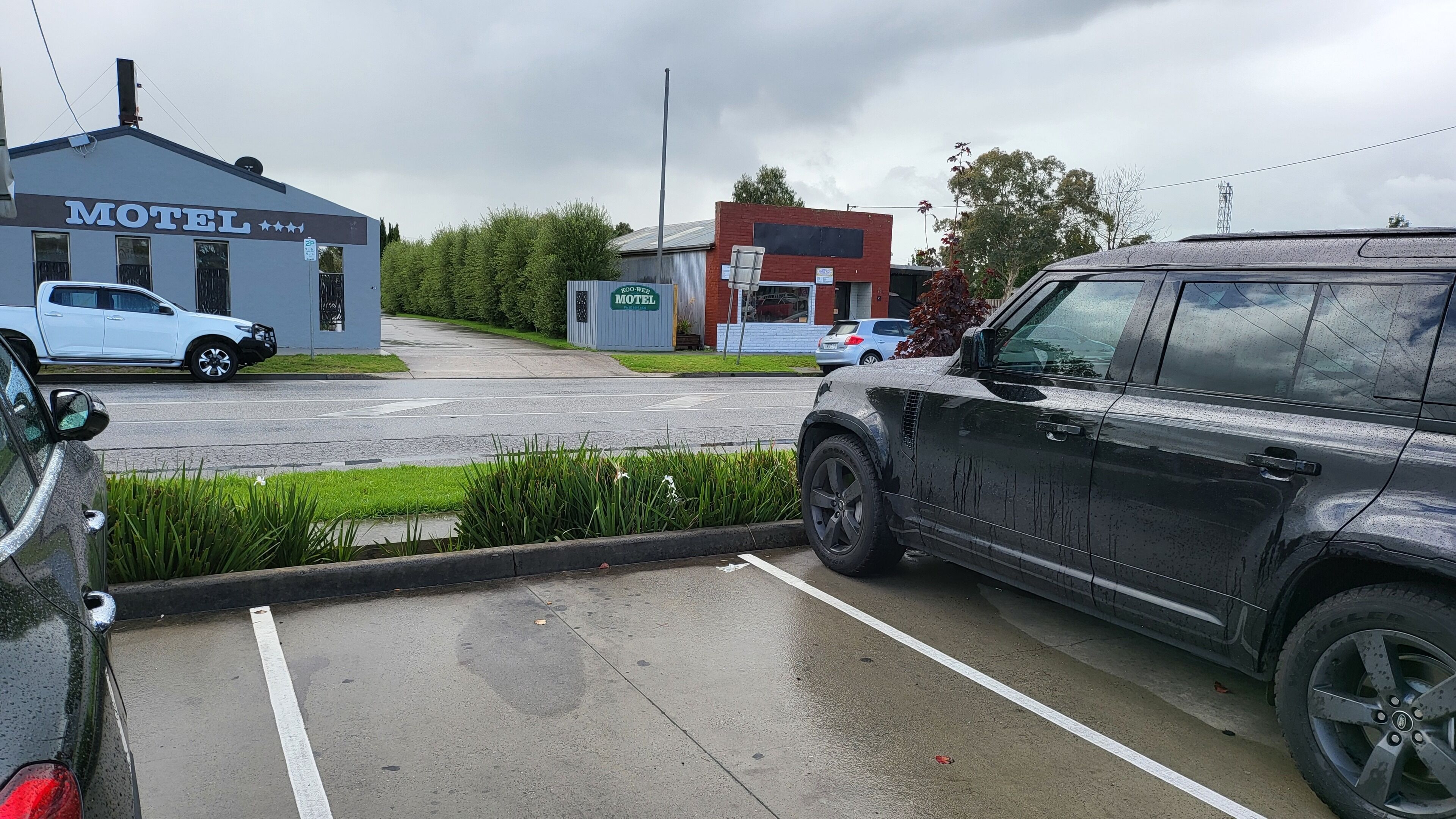 Ein Motel mit Schild, Parkplatz und einem Gebäude im Hintergrund.