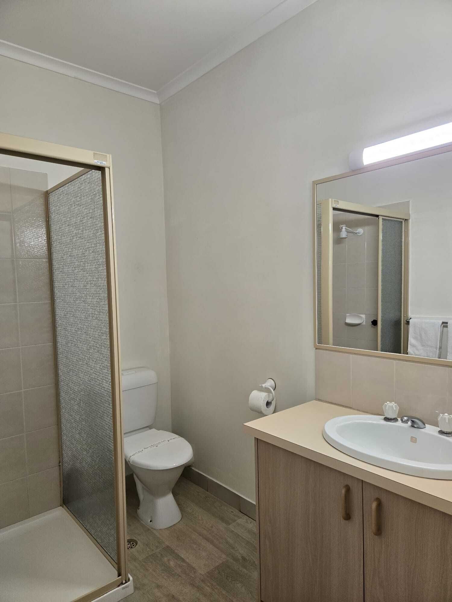 Egy fürdőszoba, amelyben WC, mosdókagyló és zuhanyzó található.