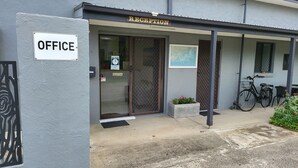 Un edificio con recepción, un letrero de oficina y una bicicleta estacionada afuera.