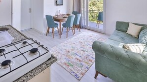 A compact living space with a kitchenette, dining area, and a green sofa. - Kaya Apart  (Kas)