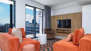 Een moderne woonkamer met oranje banken, een witte salontafel en een kamerbreed tapijt met een patroon.