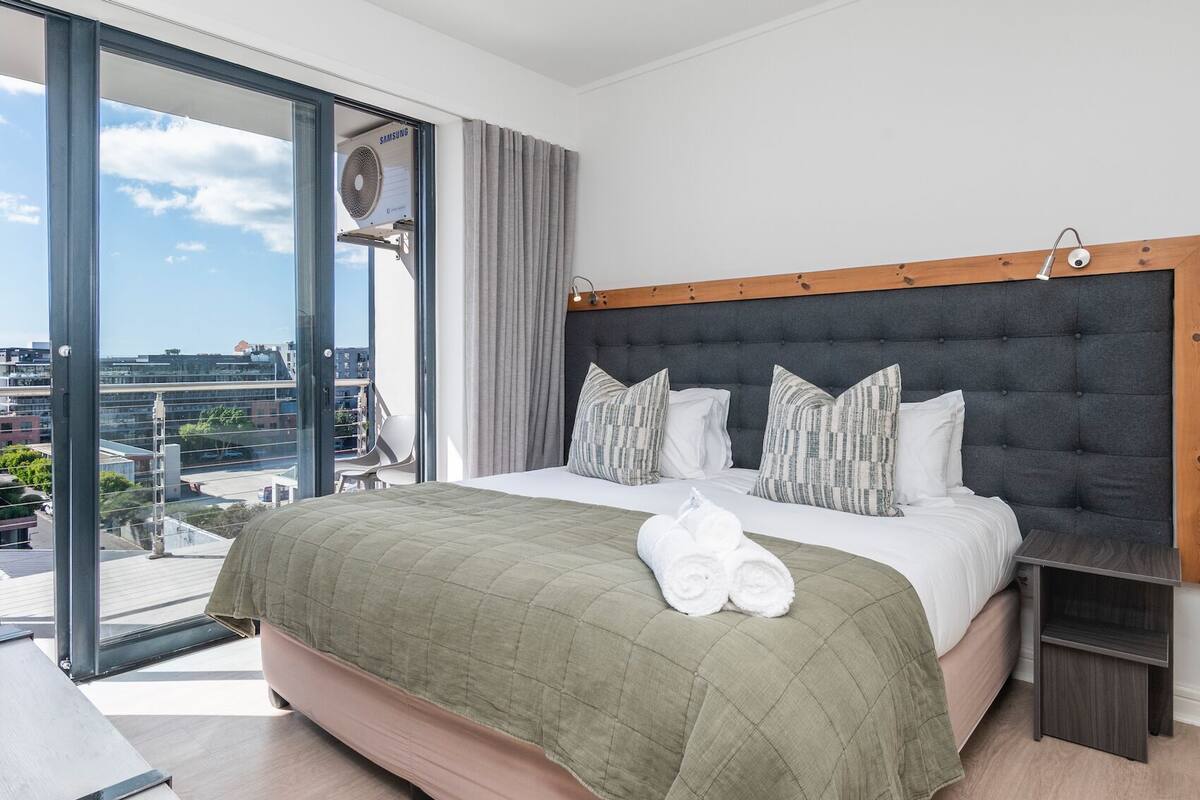 Een hotelkamer met een groot bed, uitzicht op de stad en een Samsung airconditioner.
