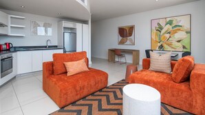 Een moderne woonkamer met oranje banken, een eethoek en een keuken.