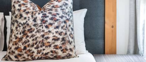 A neatly made bed with a patterned pillow, a wooden headboard, and a bedside table.